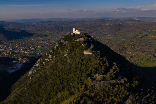 Aerial view of the Santuario del Santissimo Salvatore perched on a lush forested hilltop with a winding road and valley views in Montella Campania Italy. Aerial view of the Santuario del Santissimo Salvatore perched on a lush forested hilltop with a winding road and valley views in Montella Campania Italy.
