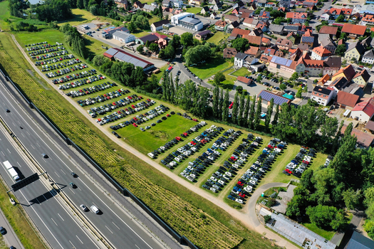 Geiselwind Germany 21 June 2025 Aerial view of Eventzentrum Strohofer Geiselwind musichall with a large parking lot full of cars next to the highway and residential houses. Geiselwind Germany 21 June 2025 Aerial view of Eventzentrum Strohofer Geiselwind musichall with a large parking lot full of cars next to the highway and residential houses.
