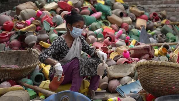 View of a woman sorting plastic and clay pots in Jashore Bangladesh. View of a woman sorting plastic and clay pots in Jashore Bangladesh.
