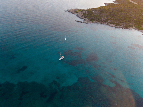 Aerial view of two sailboats floating in the clear turquoise waters of the Mediterranean Sea near the rocky coastline of Marinella Sardegna Italy. Aerial view of two sailboats floating in the clear turquoise waters of the Mediterranean Sea near the rocky coastline of Marinella Sardegna Italy.