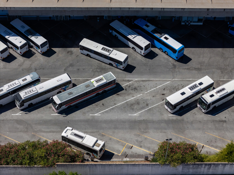 Aerial view of multiple buses parked in a terminal area with marked parking spaces and surrounding greenery Evora Evora District Portugal. Aerial view of multiple buses parked in a terminal area with marked parking spaces and surrounding greenery Evora Evora District Portugal.