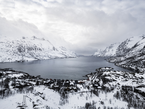 Aerial view of the Ersfjorden fjord surrounded by snow covered mountains and a small coastal village Ersfjord Troms Norway. Aerial view of the Ersfjorden fjord surrounded by snow covered mountains and a small coastal village Ersfjord Troms Norway.