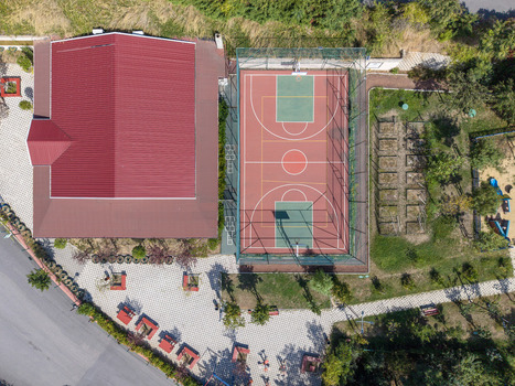 Aerial view of a basketball court next to a building with a red roof surrounded by paved walkways and green trees in Istanbul Istanbul Turkiye. Aerial view of a basketball court next to a building with a red roof surrounded by paved walkways and green trees in Istanbul Istanbul Turkiye.