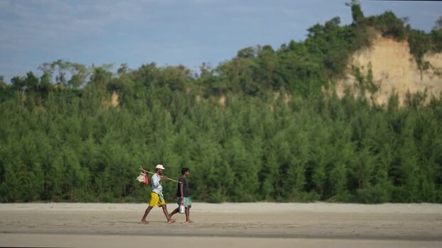 View of two men walking on the sandy beach in Cox s Bazar Bangladesh.
