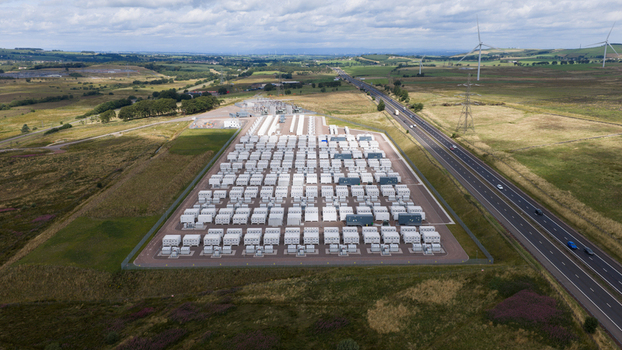Aerial view of the Coalburn Battery Energy Storage System with rows of white battery containers and a substation next to a highway in the rural landscape of Coalburn Scotland United Kingdom.