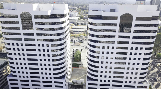 Aerial view of two modern office towers with white facades and dark glass windows featuring geometric lines in Los Angeles California United States.