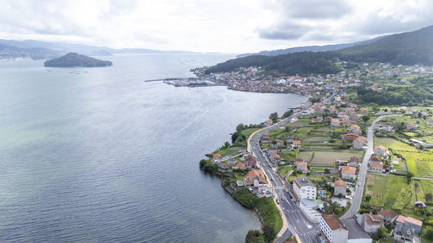 Aerial view of the coastal town of Casalvito featuring traditional houses and a winding road along the blue waters of the bay under a cloudy sky Casalvito Pontevedra Spain. Aerial view of the coastal town of Casalvito featuring traditional houses and a winding road along the blue waters of the bay under a cloudy sky Casalvito Pontevedra Spain.
