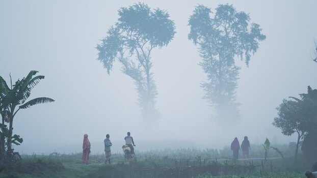 View of people walking and cycling in thick fog in Bogura Bangladesh.