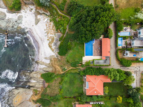 Aerial view of luxury villas with red tiled roofs and swimming pools situated along the rocky coastline of the Black Sea in Lozenets Burgas Bulgaria.
