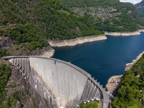 Aerial view of the massive Verzasca Dam and the deep blue waters of Lago di Vogorno surrounded by lush green mountains in Gordola Ticino Switzerland. Aerial view of the massive Verzasca Dam and the deep blue waters of Lago di Vogorno surrounded by lush green mountains in Gordola Ticino Switzerland.