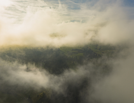Aerial view of alpine meadows emerging through dense morning fog and low clouds in the Italian Dolomites Seis am Schlern Trentino Alto Adige Italy.