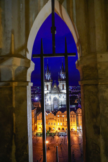 Aerial view of the illuminated Church of Our Lady before Tyn rising above the historic Old Town Square at night framed by a stone archway in Prague Prague Czechia. Aerial view of the illuminated Church of Our Lady before Tyn rising above the historic Old Town Square at night framed by a stone archway in Prague Prague Czechia.