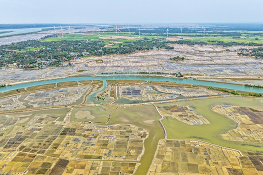Aerial view of a patchwork of land and waterways with wind turbines standing tall in the distance Cox s Bazar Chittagong Division Bangladesh. Aerial view of a patchwork of land and waterways with wind turbines standing tall in the distance Cox s Bazar Chittagong Division Bangladesh.