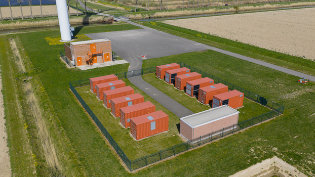 Drone view of wind turbines and a battery storage facility distributing renewable energy supporting grid balance clean power infrastructure and sustainable electricity supply.