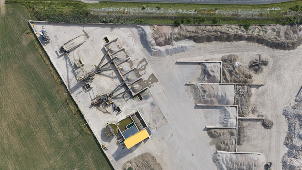 Aerial view of a gravel and sand processing plant featuring conveyor belts industrial machinery and large stockpiles of aggregate in La Longueville Hauts de France France.
