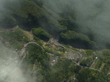 Aerial view of Tambang Pasir Merapi Kali Gendol Sand Mine with winding roads lush green forests and misty clouds in Kecamatan Cangkringan Daerah Istimewa Yogya Indonesia. Aerial view of Tambang Pasir Merapi Kali Gendol Sand Mine with winding roads lush green forests and misty clouds in Kecamatan Cangkringan Daerah Istimewa Yogya Indonesia.
