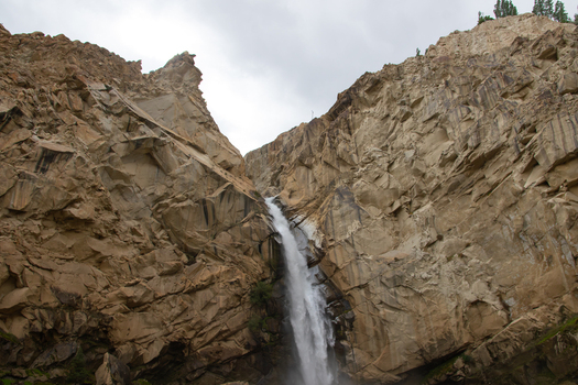 View of Khamosh Waterfall cascading down steep rocky cliffs under an overcast sky in Skardu Gilgit Pakistan.