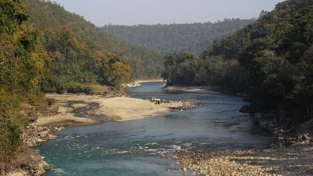 View of a wide river flowing through a forested valley Nepal.