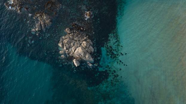 Aerial view of the rugged coastline featuring rocky outcrops surrounded by clear turquoise waters along the shore in Plevenon Brittany France. Aerial view of the rugged coastline featuring rocky outcrops surrounded by clear turquoise waters along the shore in Plevenon Brittany France.