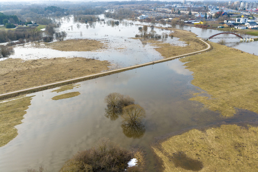 Aerial view of the flooded Nevezis river valley with submerged meadows a pedestrian arch bridge and a walking path under an overcast sky in Kedainiai Kaunas County Lithuania. Aerial view of the flooded Nevezis river valley with submerged meadows a pedestrian arch bridge and a walking path under an overcast sky in Kedainiai Kaunas County Lithuania.