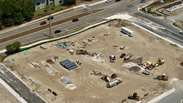 Aerial view of the construction site at Foundry Lane featuring heavy machinery excavators and industrial pipes under a clear sky in World Golf Village Florida United States.