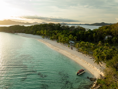Aerial view of Malcapuya Island featuring a pristine white sand beach turquoise waters lush palm trees and a small boat anchored near the shore in Coron Mimaropa Philippines. Aerial view of Malcapuya Island featuring a pristine white sand beach turquoise waters lush palm trees and a small boat anchored near the shore in Coron Mimaropa Philippines.