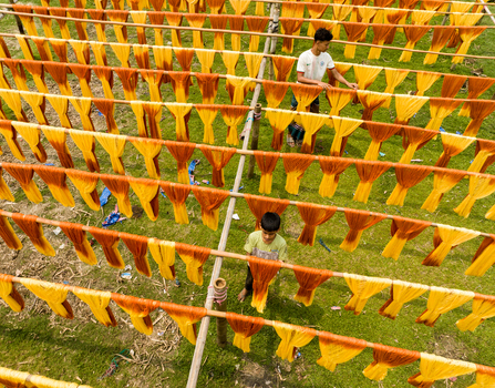 Narayanganj Bangladesh 30 March 2026 Aerial view of vibrant fabrics drying on bamboo frames creating a colorful tapestry against the lush green backdrop.