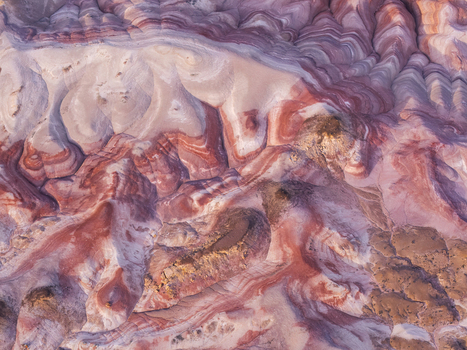 Aerial view of the colorful striped clay mounds of the Bentonite Hills with vibrant red purple and white geological layers in the desert landscape of Hanksville Utah United States.