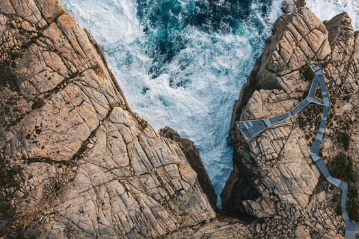 Aerial view of The Gap a dramatic rock formation with a steel viewing platform overlooking crashing waves against rugged granite cliffs in Torndirrup Western Australia Australia. Aerial view of The Gap a dramatic rock formation with a steel viewing platform overlooking crashing waves against rugged granite cliffs in Torndirrup Western Australia Australia.