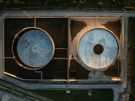 Aerial view of two large industrial storage tanks surrounded by pipelines and access roads during sunset in Augusta Sicily Italy. Aerial view of two large industrial storage tanks surrounded by pipelines and access roads during sunset in Augusta Sicily Italy.
