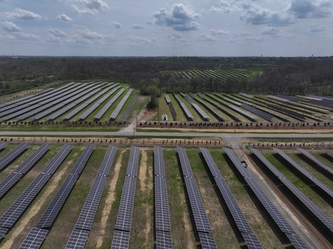 Lebanon United States 12 April 2026 Aerial view of a large solar farm with rows of photovoltaic panels surrounded by dense green forest under a cloudy sky.