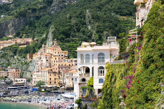 Aerial view of the coastal town of Amalfi with its historic buildings colorful houses and beach umbrellas along the Tyrrhenian Sea in Amalfi Campania Italy. Aerial view of the coastal town of Amalfi with its historic buildings colorful houses and beach umbrellas along the Tyrrhenian Sea in Amalfi Campania Italy.