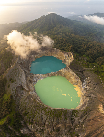 Aerial view of the vibrant turquoise and green crater lakes of Kelimutu National Park surrounded by lush volcanic mountains in Detusoko East Nusa Tenggara Indonesia.
