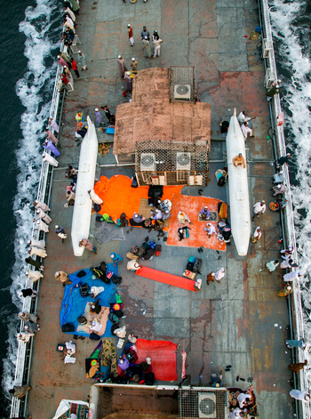 Dhaka Bangladesh 04 April 2026 Aerial view of a ferry packed with people and luggage vibrant tarps creating a mosaic of colors against the gray deck. Dhaka Bangladesh 04 April 2026 Aerial view of a ferry packed with people and luggage vibrant tarps creating a mosaic of colors against the gray deck.