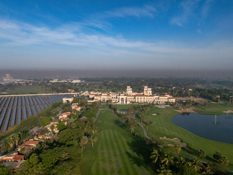 Ahmedabad Gujarat India 21 March 2026 Aerial view of Kalhaar Blues Greens Golf Club featuring lush green fairways a large lake and adjacent solar panel arrays.