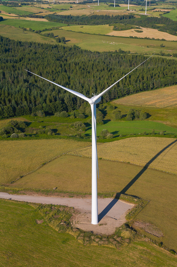 Aerial view of a solitary wind turbine standing tall against a backdrop of patchwork fields and dense woodland Salles Curan Occitanie France. Aerial view of a solitary wind turbine standing tall against a backdrop of patchwork fields and dense woodland Salles Curan Occitanie France.