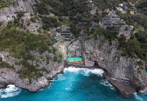 Aerial view of rugged cliffs meet the turquoise sea revealing hidden pools and terraces cascading down the steep slopes Laurito Campania Italy. Aerial view of rugged cliffs meet the turquoise sea revealing hidden pools and terraces cascading down the steep slopes Laurito Campania Italy.