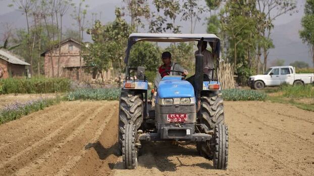 View of a blue tractor plowing a field in Dhangadhi Nepal. View of a blue tractor plowing a field in Dhangadhi Nepal.