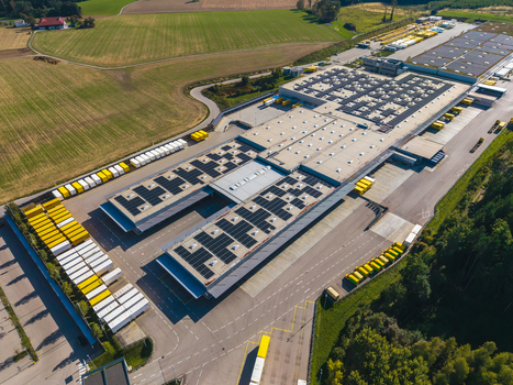 Aerial view of Logistikzentrum Allhaming featuring warehouse buildings with solar panels parking areas with trailers and surrounding fields in Allhaming Oberosterreich Austria. Aerial view of Logistikzentrum Allhaming featuring warehouse buildings with solar panels parking areas with trailers and surrounding fields in Allhaming Oberosterreich Austria.