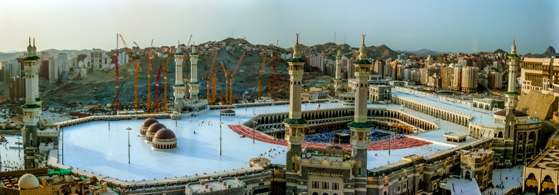 Aerial view of the Masjid al Haram mosque complex with the Kaaba at its center surrounded by tall minarets construction cranes and the urban landscape of Makkah Makkah Province Saudi Arabia. Aerial view of the Masjid al Haram mosque complex with the Kaaba at its center surrounded by tall minarets construction cranes and the urban landscape of Makkah Makkah Province Saudi Arabia.