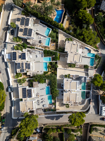 Aerial view of modern villas with private swimming pools and solar panels on rooftops in Moraira Valencian Community Spain.