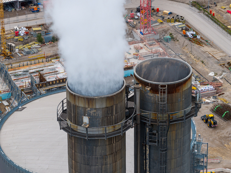 Aerial view of the Heizkraftwerk Reuter West power plant featuring large industrial chimneys with steam emission and surrounding construction site infrastructure in Berlin Berlin Germany.