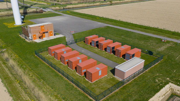 Aerial view of a battery energy storage facility with orange containers and a wind turbine base in Middelharnis South Holland Netherlands. Aerial view of a battery energy storage facility with orange containers and a wind turbine base in Middelharnis South Holland Netherlands.