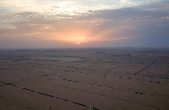 View of vast sand dunes and desert landscape under a glowing sunset sky in Dubai Dubai United Arab Emirates. View of vast sand dunes and desert landscape under a glowing sunset sky in Dubai Dubai United Arab Emirates.