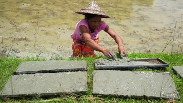 View of a woman in a conical hat working with mud Bangladesh.