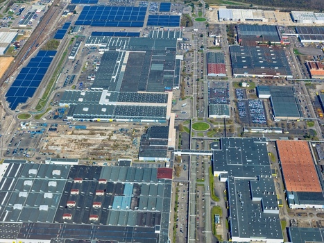 Aerial view of sprawling industrial rooftops bask under the sun interspersed with solar panels roads and green spaces Sausheim Grand Est France.