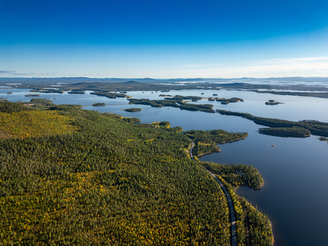 Aerial view of Galtispuoda overlooking the vast lake system dense coniferous forests and a winding road along the shoreline in Arjeplog Norrbotten County Sweden.
