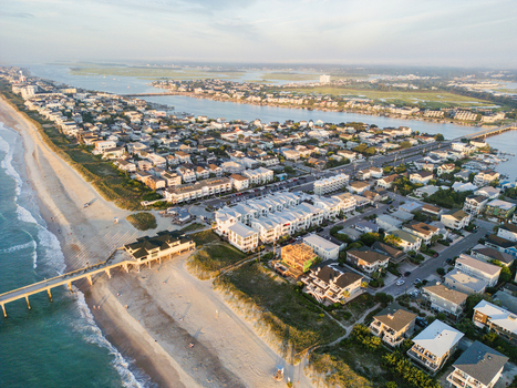 Aerial view of the sandy coastline a wooden pier and residential buildings along the shore in Wrightsville Beach North Carolina United States.