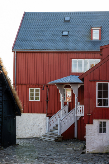 View of a traditional red wooden house with a white stone base white staircase and slate roof in the Faroe Islands. View of a traditional red wooden house with a white stone base white staircase and slate roof in the Faroe Islands.