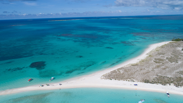 Aerial view of Los Roques archipelago featuring white sand beaches turquoise waters and small boats anchored near the shore in Los Roques Dependencias Federales Venezuela. Aerial view of Los Roques archipelago featuring white sand beaches turquoise waters and small boats anchored near the shore in Los Roques Dependencias Federales Venezuela.